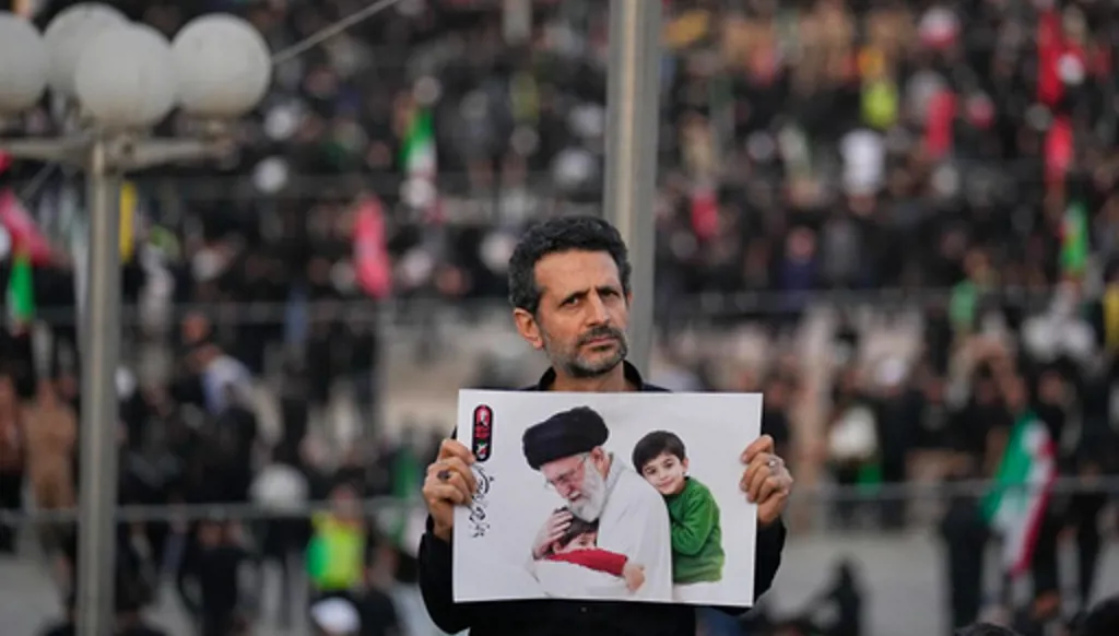 A man holds a picture of slain Iranian Supreme Leader Ayatollah Ali Khamenei as a crowd waits for his casket to arrive at the Imam Khomeini Mosalla Grand Mosque for the start of the dayslong funeral ceremonies in Tehran, Iran, Saturday, July 4, 2026. (AP Photo/Altaf Qadri)
