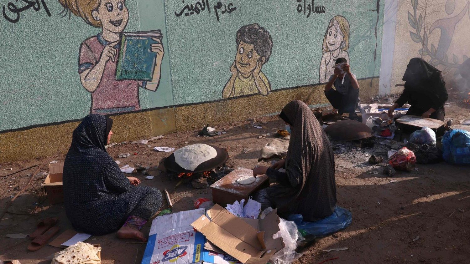 نساء فلسطينيات يخبزن الخبز داخل مأوى للعائلات النازحة في مدرسة في رفح، جنوب قطاع غزة. 
