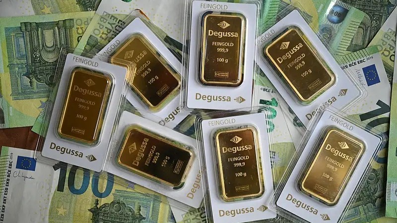 سبائك ذهبية بحجم 100 غرام من شركة ديغوسا الألمانية لتجارة المعادن الثمينة تظهر على أوراق نقدية بقيمة 100 يورو في دورتموند، غرب ألمانيا.. (فرانس برس)