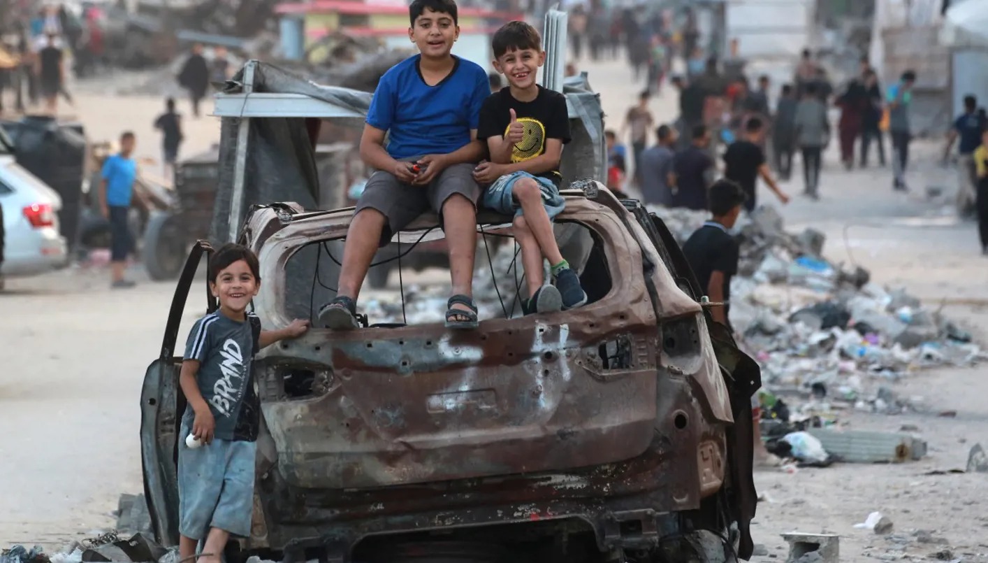 أطفال على سيارة مدمرة في غزّة (أ ف ب).
