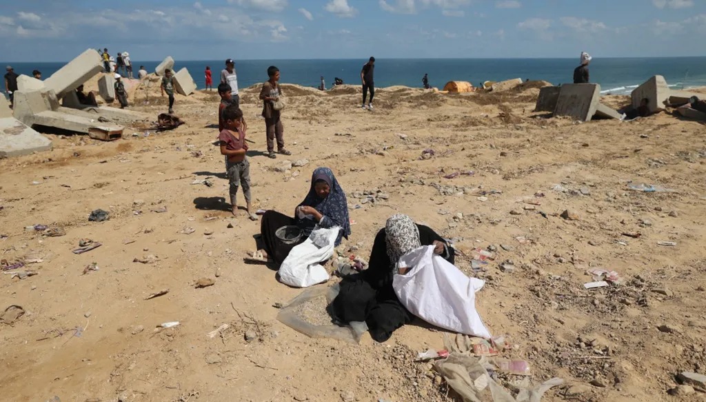 فلسطينيون يبحثون عن الحبوب في الرمال. (أ ف ب)