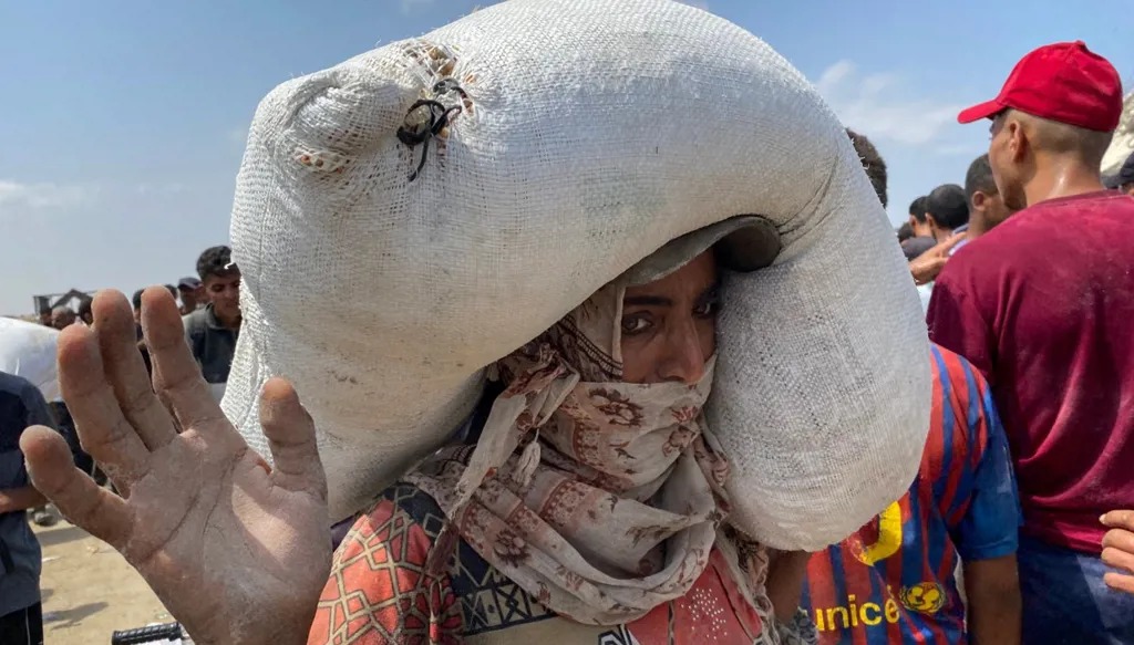 سيدة فلسطينية تحمل كيس مساعدات في خان يونس. (أ ف ب)