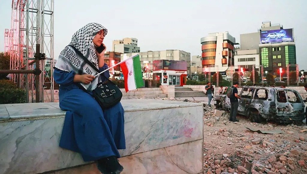 إيرانية أمام موقع قصفته إسرائيل في طهران. (أ ف ب)