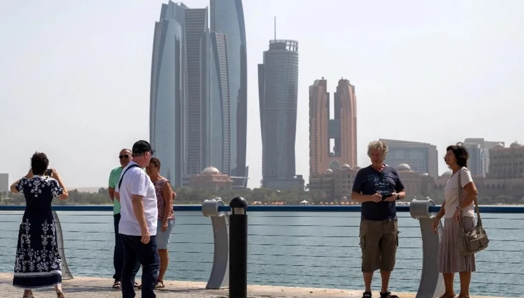 سياح بالقرب من أبراج الاتحاد في أبو ظبي. (أ ف ب)