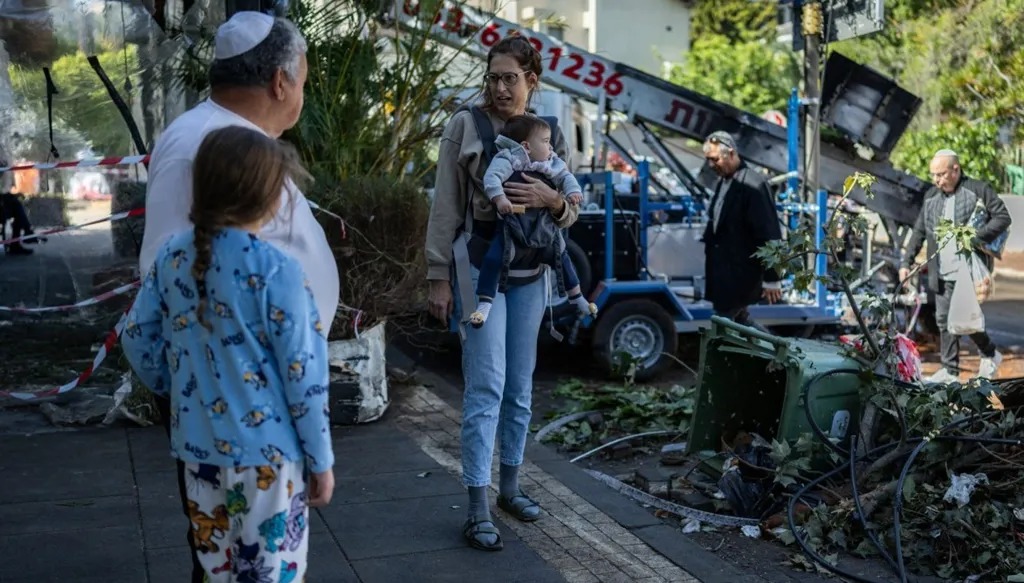 إسرائيليون يتفقدون الأضرار في موقع أصابته شظايا صاروخ إيراني في رامات غان. (أ ف ب)