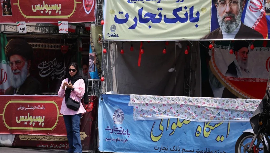 سيدة إيرانية تقف تحت لافتة تحمل صورة المرشد الأعلى الإيراني آية الله مجتبى خامنئي، في طهران. (أ ف ب)