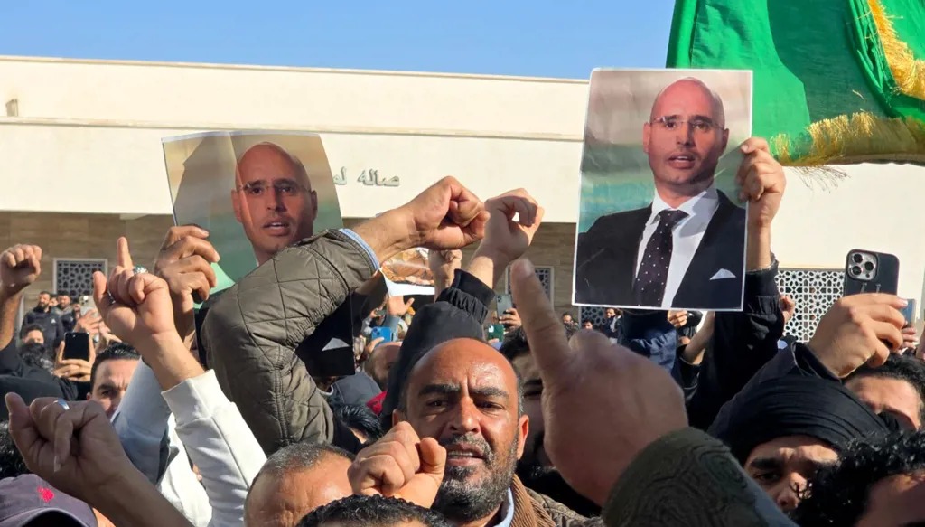 مشاركون في جنازة سيف الإسلام القذافي يرفعون صوره. (أ ف ب)