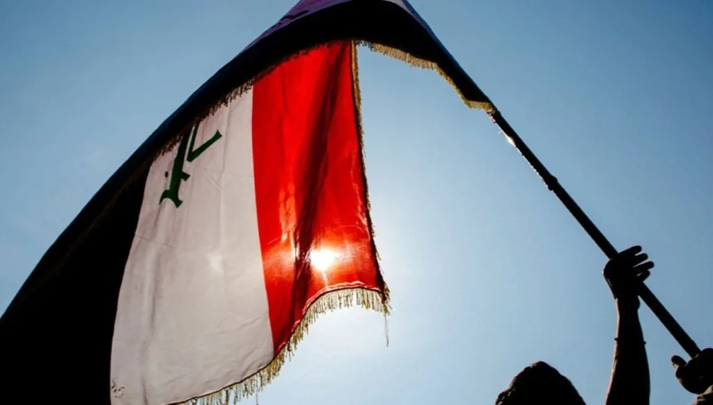 عراقي يُلوّح بعلم بلاده في أحد شوارع البصرة. (أ ف ب)