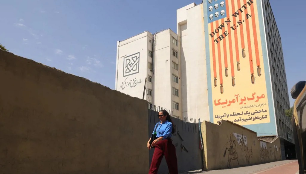 سيدة إيرانية تمر أمام لافتة مناهضة للولايات المتحدة في طهران، 19 تموز/يوليو 2026. (أ ف ب)