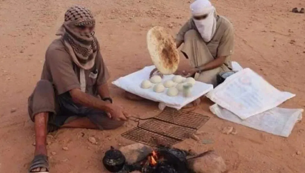 عناصر قال "داعش" إنهم من مقاتليه في جنوب ليبيا، خلال إفطار جماعي ظهرت فيه أسلحة، ضمن صور دعائية نشرها التنظيم في رمضان عام 2022. (إعلام التنظيم)