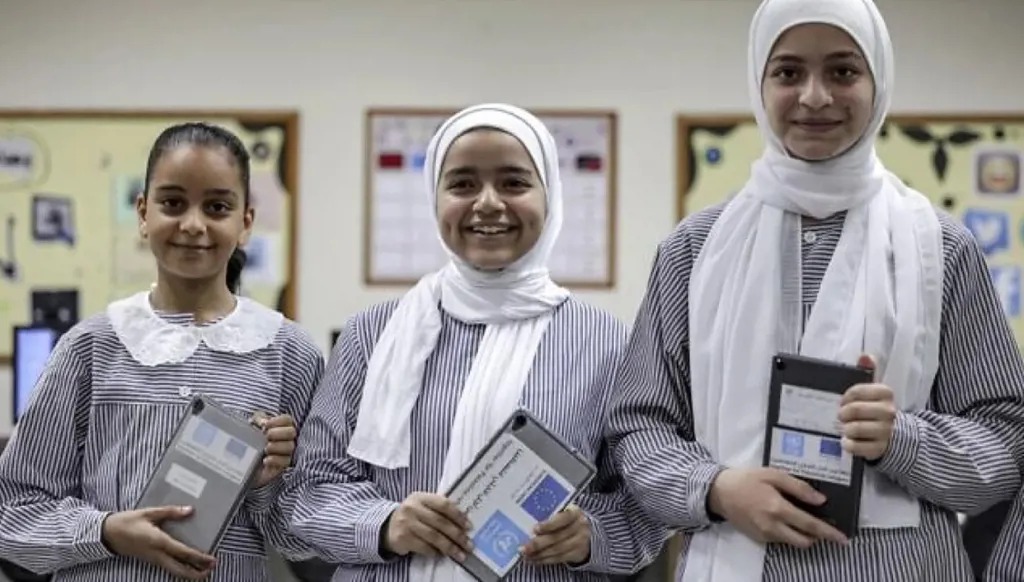 طالبات في غزة يحملن أجهزة لوحية قدمتها الأمم المتحدة في صورة من الأرشيف (رويترز)