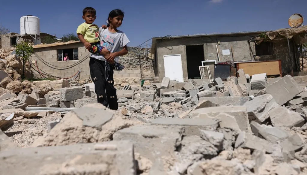 أطفال فلسطينيون يقفون وسط أنقاض منزل تم هدمه مع أكثر من 20 مبنى آخر في الضفة الغربية المحتلة، في 23 سبتمبر 2026. (أ ف ب)