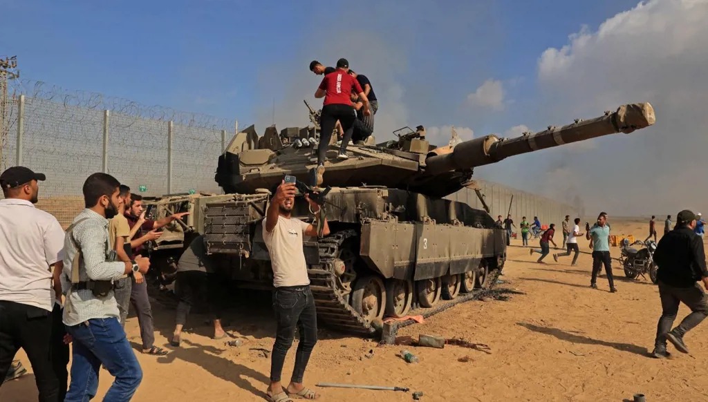 فلسطينيون يسيطرون على دبابة إسرائيلية بعد عبور السياج الحدودي مع إسرائيل من خان يونس في جنوب قطاع غزة، 7 أكتوبر 2023. (أ ف ب)
