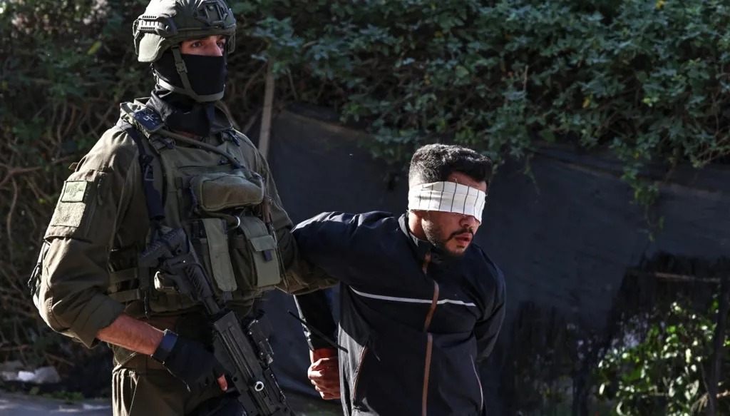 جندي إسرائيلي يعتقل فلسطينياً خلال عملية عسكرية في بلدة قلقيلية بالضفة الغربية. (أ ف ب)