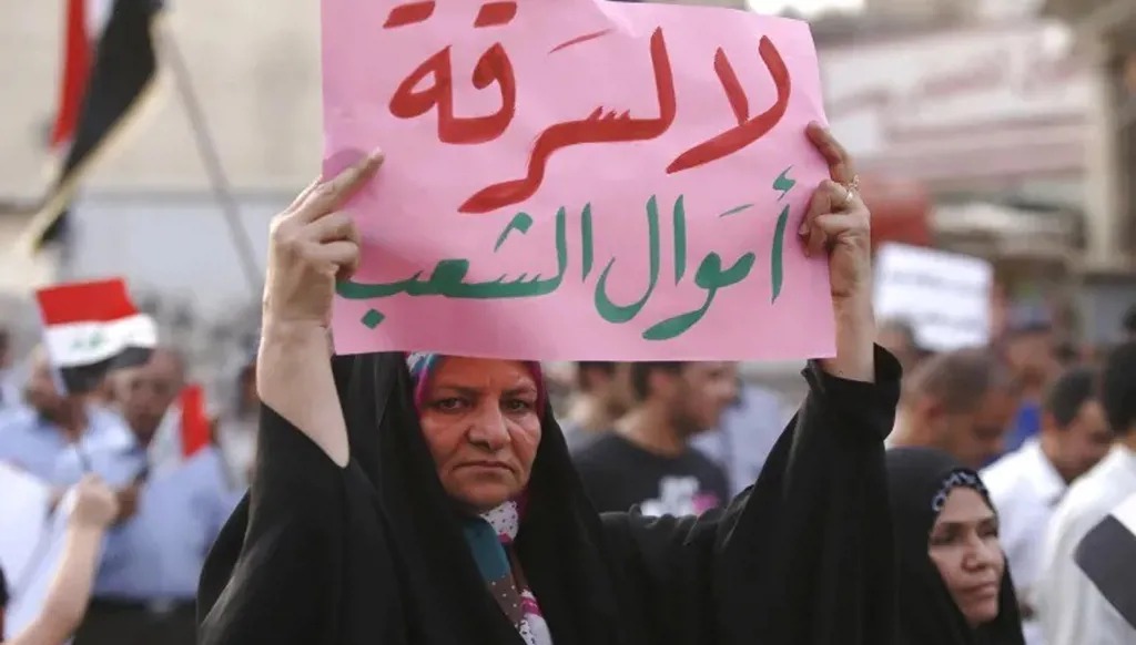 سيّدة عراقية تحمل لافتة خلال تظاهرة سابقة ضد الفساد في البلاد. (أ ف ب – أرشيف)