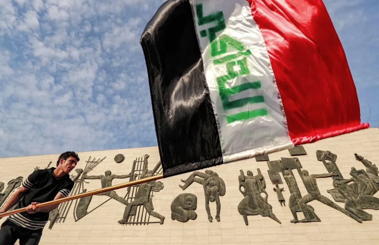 رجل يلوح في العلم العراقي في بغداد (أ ف ب)