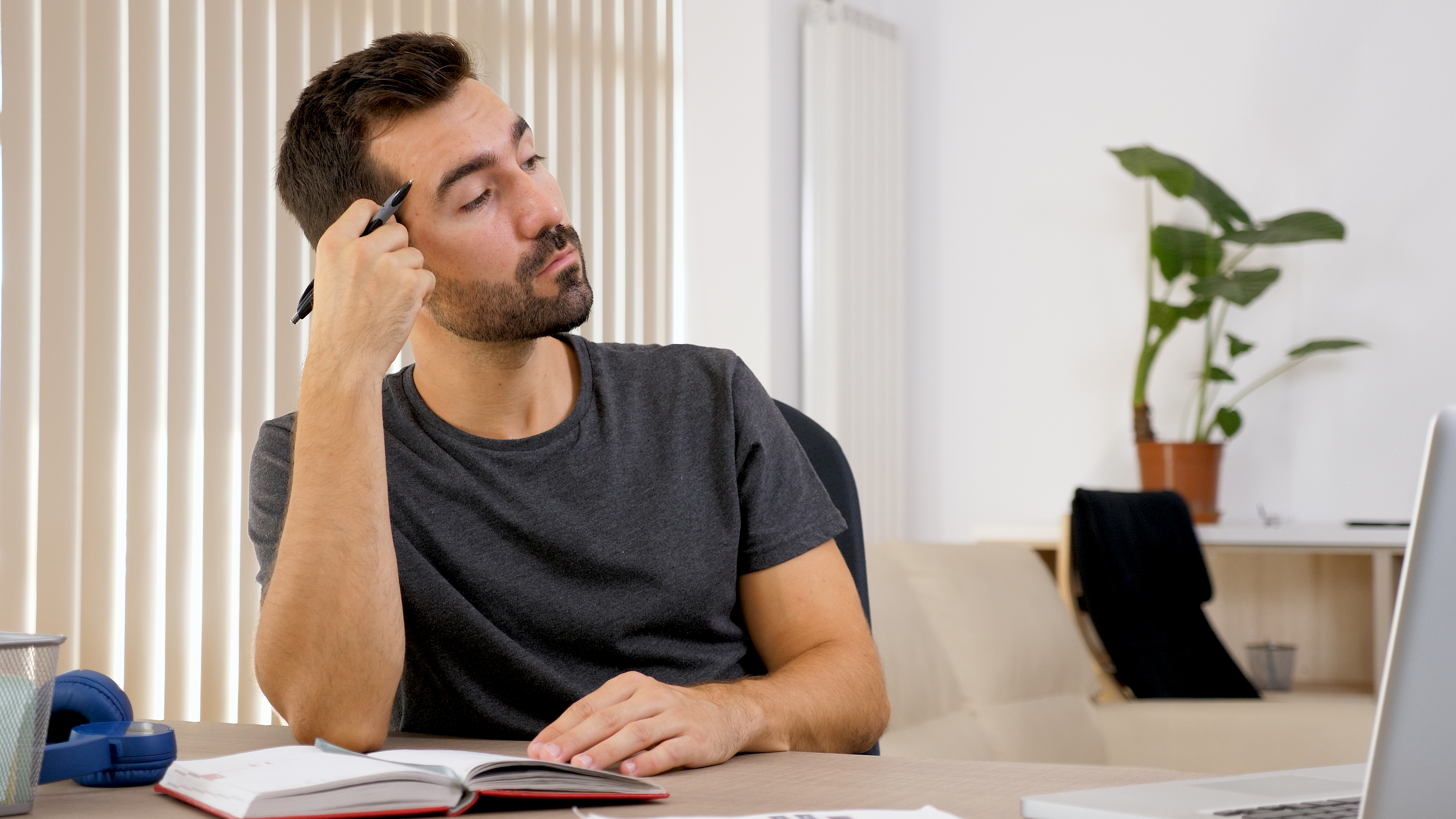 رجل يكتب في دفتر ملاحظات على مكتبه، ويدوّن أفكاره على الورق. (magnific).