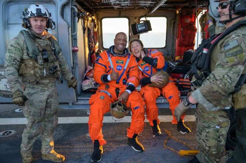 فيكتور غلوفر وكريستينا كوك على متن مروحية MH-60 Seahawk التابعة للبحرية الأميركية بعد هبوط الكبسولة يوم الجمعة (ناسا)