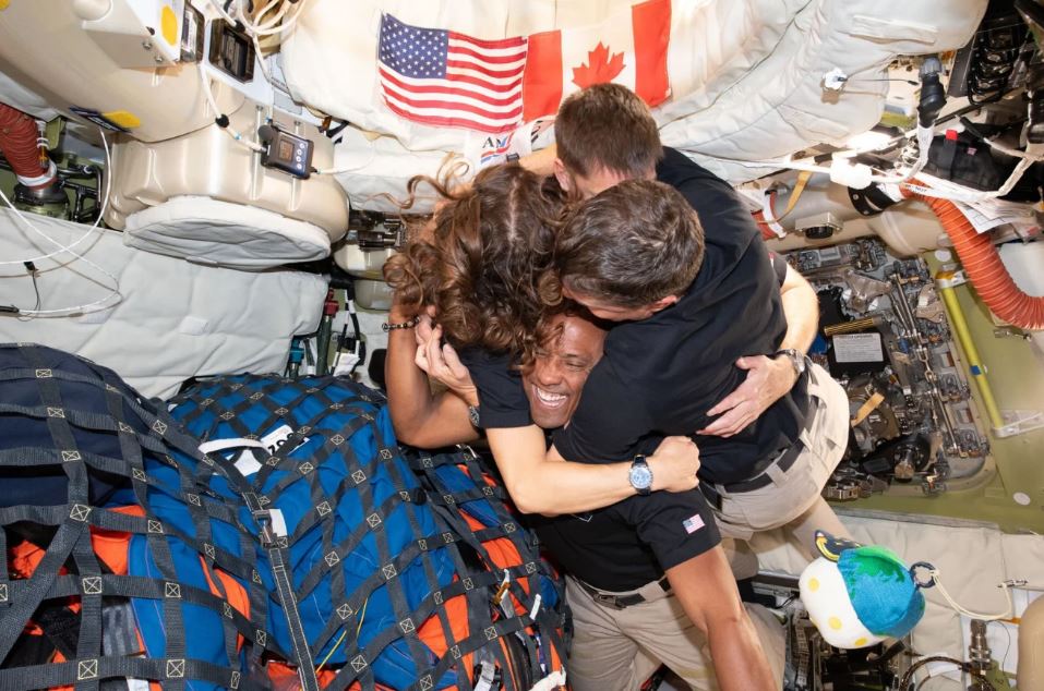 عناق كريستينا كوك، جيريمي هانسن، ريد وايزمان وفيكتور غلوفر من مهمة Artemis II داخل كبسولة Orion في 7 نيسان (ناسا)