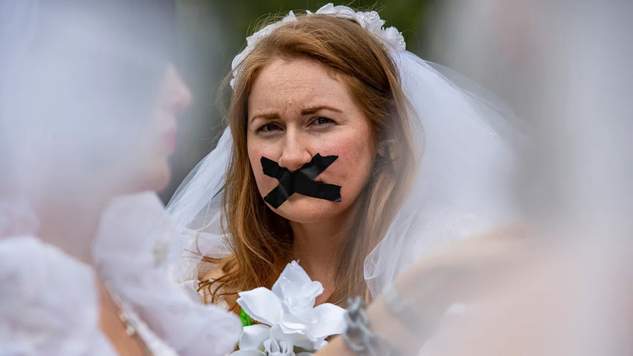 صورة تعبيرية- مدافعات وناجيات من زواج الأطفال من مجموعة Unchained at Last يرتدين فساتين اعراس ويضعن سلاسل في ايديهن، وأشرطة لاصقه على أفواههن، أثناء تجمعهن في بوسطن كومون قبل السير إلى مقر الولاية للدعوة إلى إنهاء زواج الأطفال في بوسطن بماساتشوستس في 22 أيلول 2021 (أ ف ب).