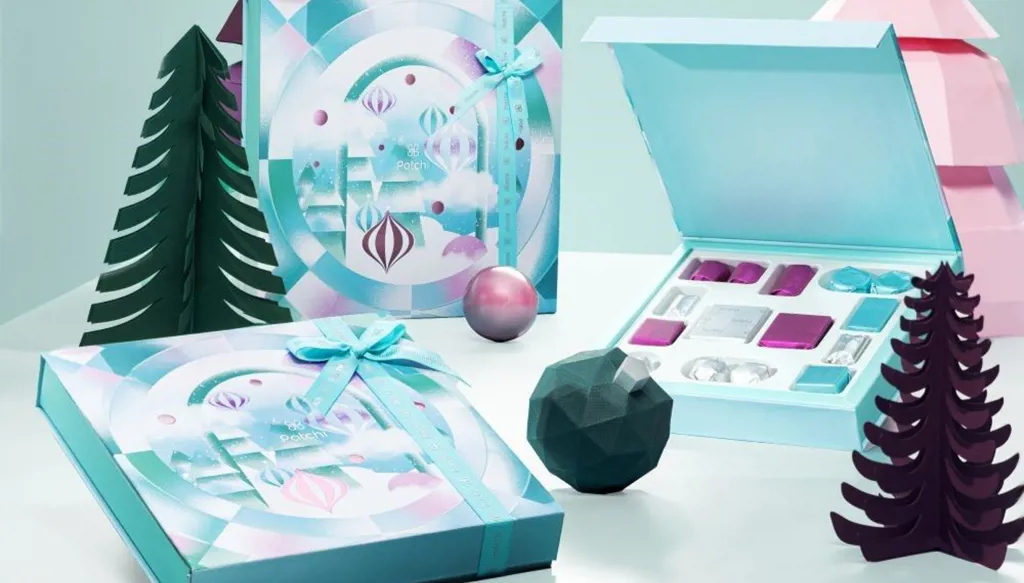 ثلاثة صناديق هدايا فاخرة تُعرض وسط ديكورات احتفالية وأشجار ملونة مصنوعة من الورق.