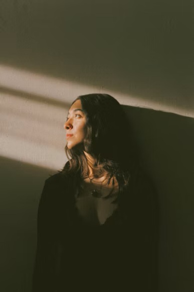 امرأة يلامس الضوء وجهها في لحظة هدوء وتأمّل. (Zyanya Citlalli / Unsplash)