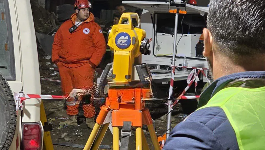 الصليب الأحمر يستخدم جهاز ليزر لفحص المبنى المقابل للمبنى المنهار وتقييم خطر انهياره