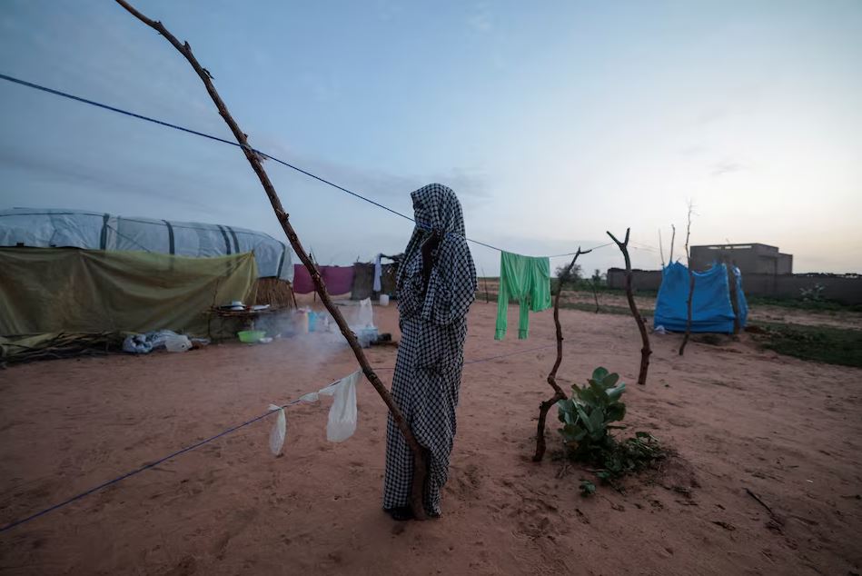 طالبة تبلغ من العمر 20 عاماً، تقول إنها تعرّضت للاغتصاب غرب دارفور، بعدما فُصلت عن عائلتها أثناء رحلة الفرار، تقف أمام مأوى مؤقت في أدري، تشاد، في 1 آب/أغسطس 2023 (رويترز)