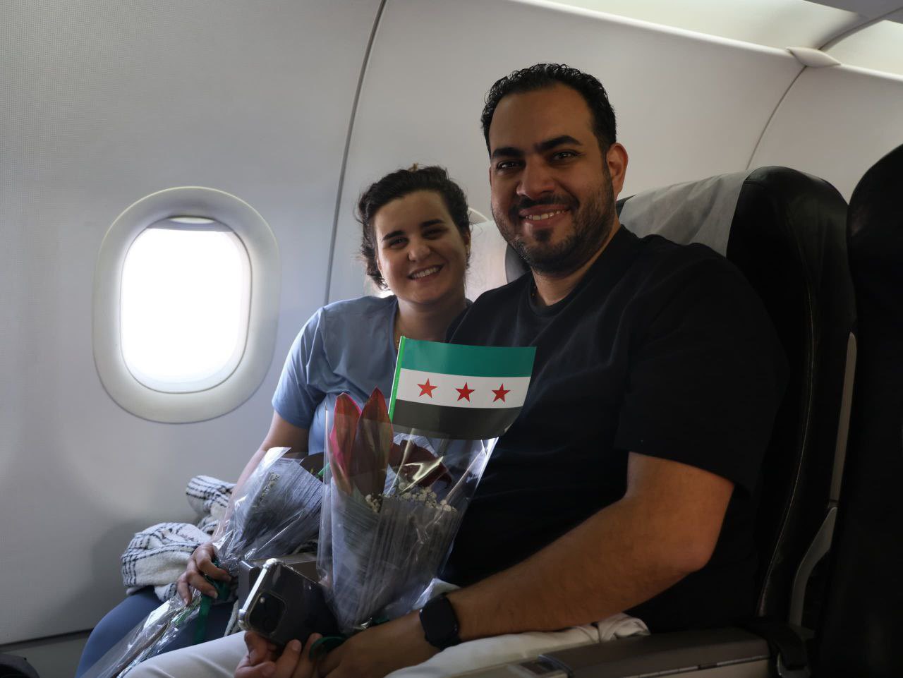 مسافران عبر الخطوط الجوية السورية يحملان العلم السوري الجديد (أكس)‏