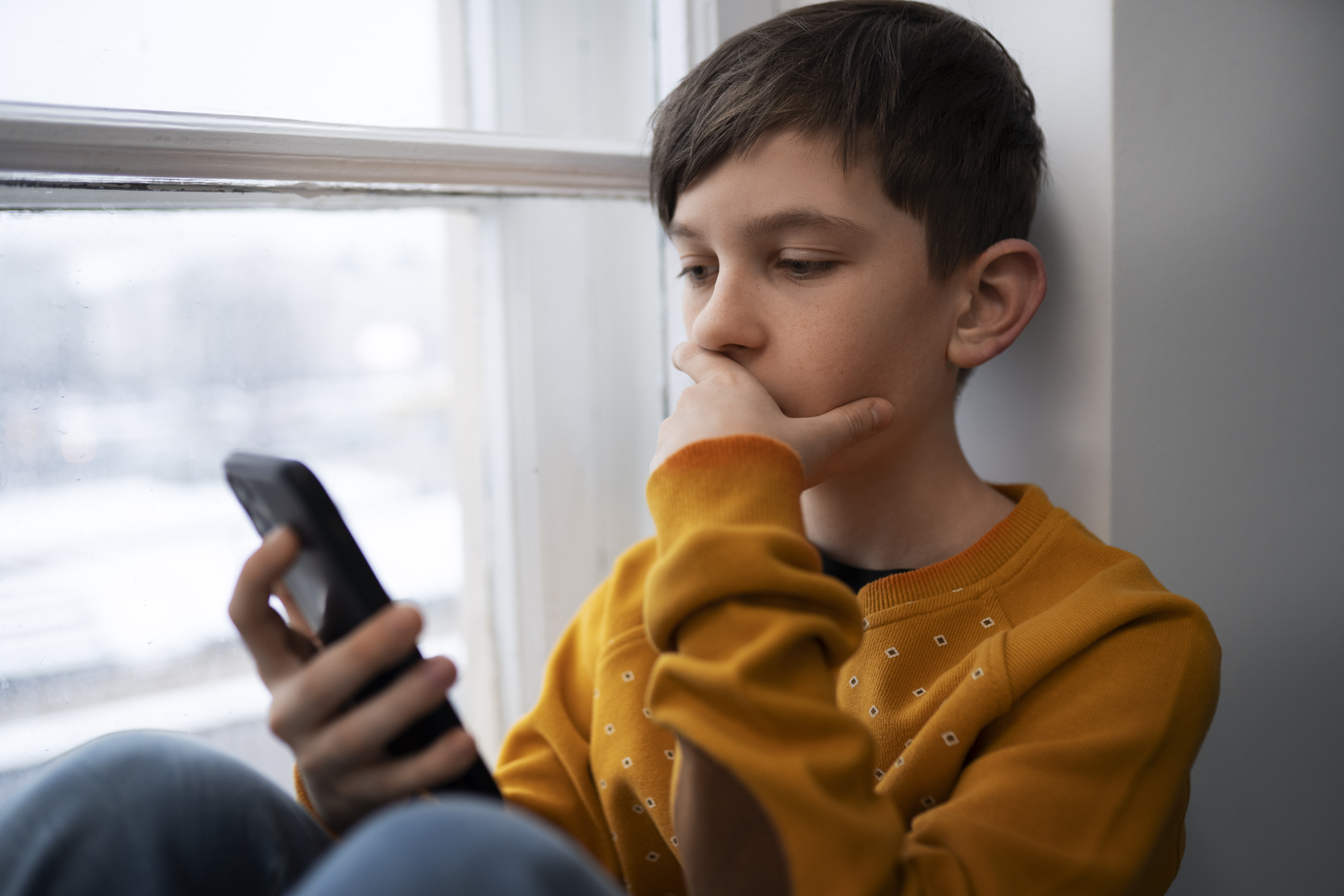 طفل صغير يستخدم الهاتف الذكي (Freepik).