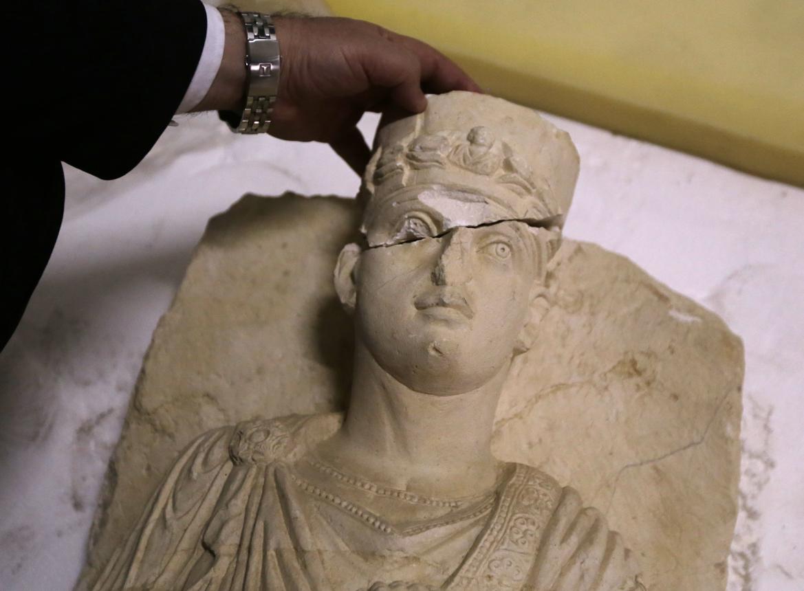 يد تعيد ترميم تمثال جنائزي من تدمر تضرّر خلال الحرب. (AFP)