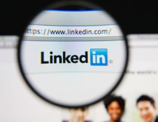 صورة تعبيرية لشعار منصة لينكدإن (LinkedIn) عبر عدسة مكبرة على شاشة حاسوب.
