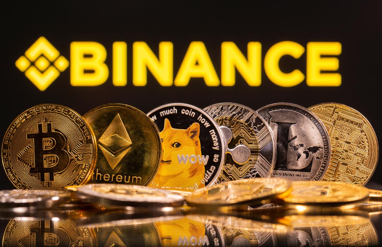 شعار منصة بينانس لتداول العملات المشفّرة، أمام مجموعة من العملات الرقمية
