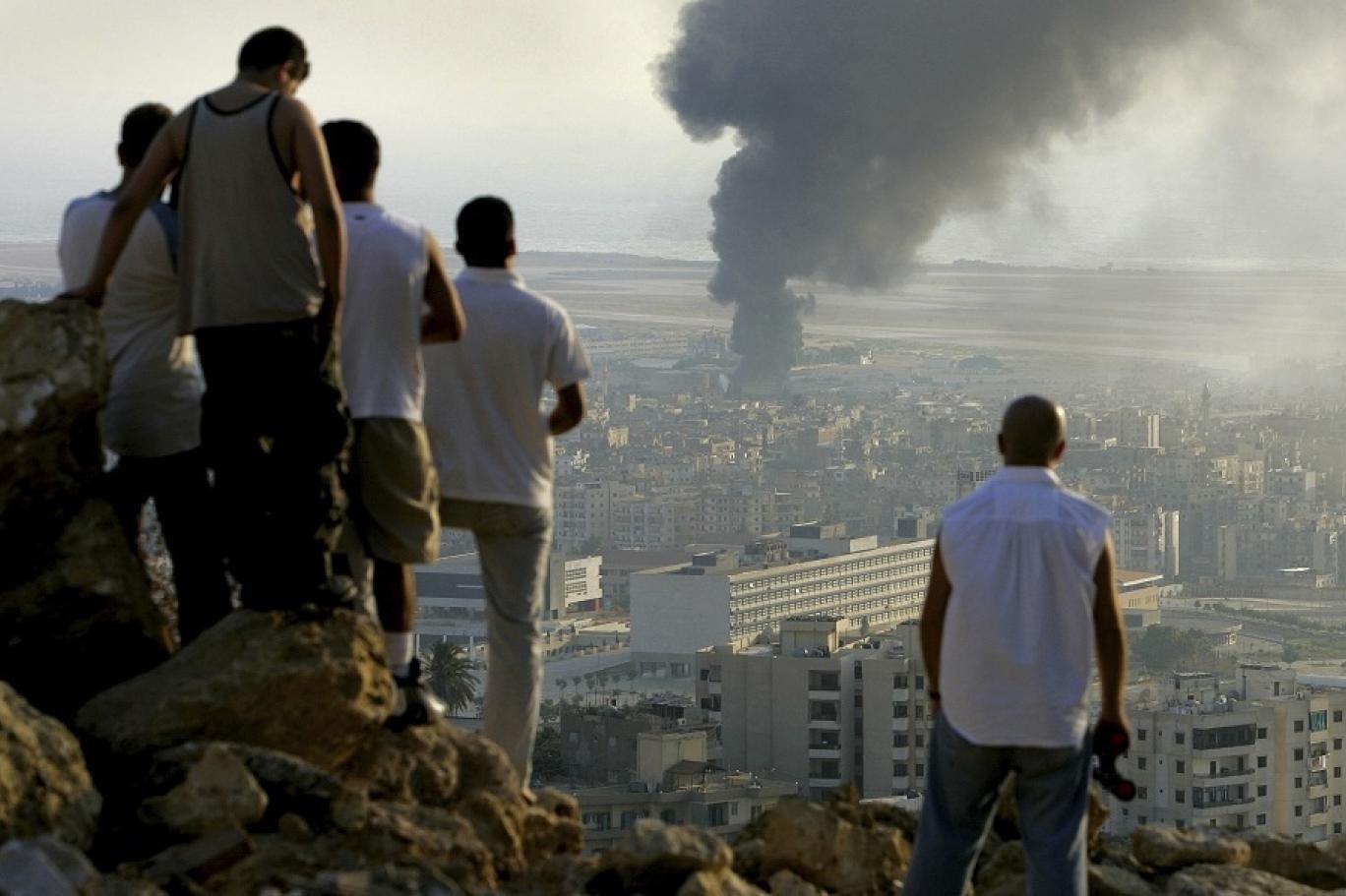 Lebanese youths watch smoke billow from a fuel storage facility at Beirut International Airport after it was hit by an Israeli airstrike on July 14, 2006. (AP)