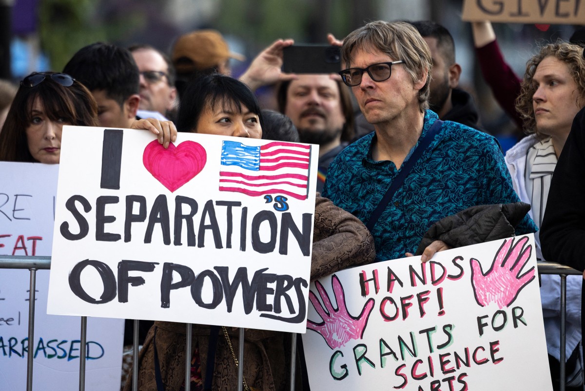 متظاهرون يرفعون لافتات ”ارفعوا أيديكم!“ التي عمت البلاد ضد ترامب في لوس أنجلوس. (أ ف ب) 