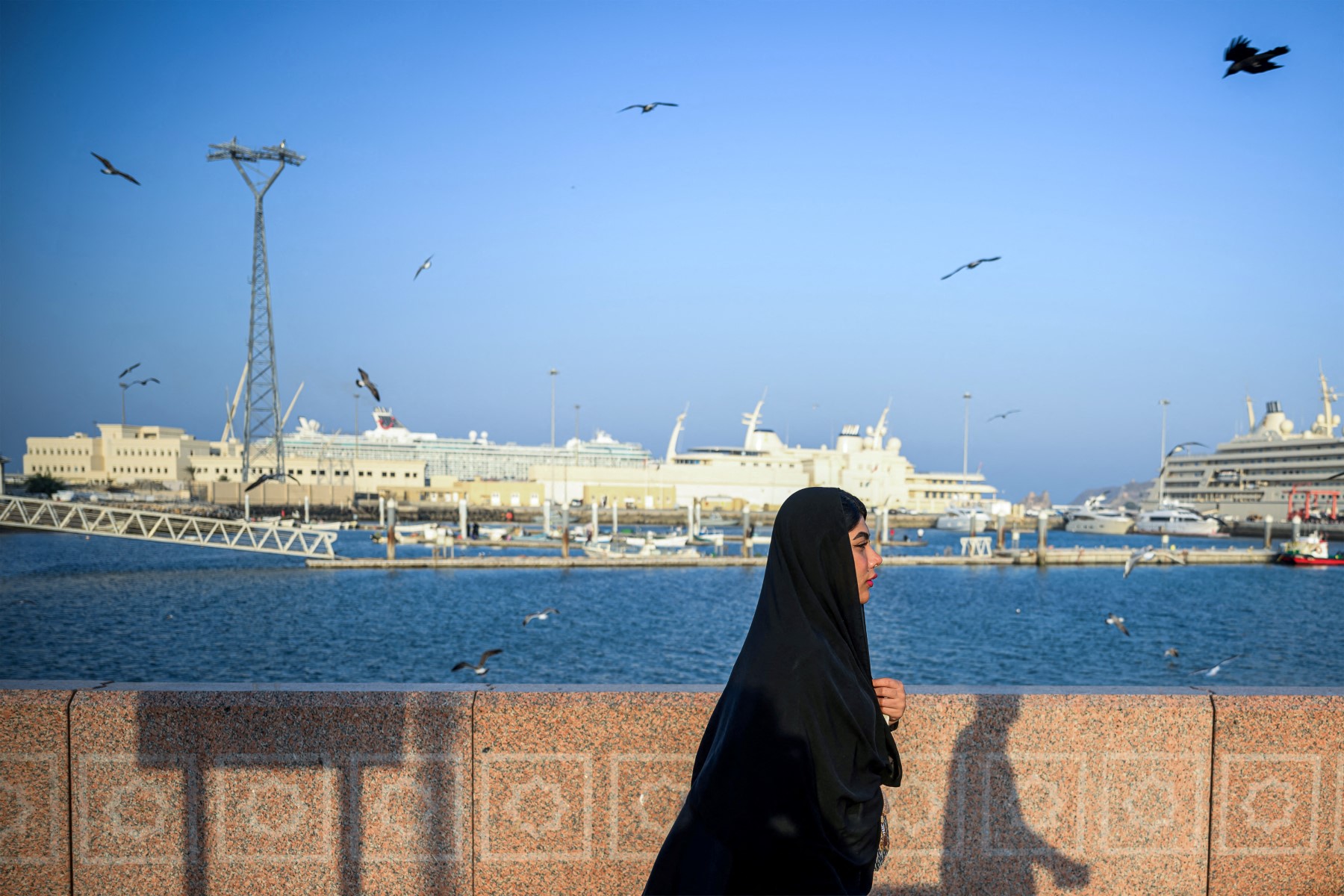 امرأة تسير على طول كورنيش مسقط، عاصمة سلطنة عمان (أ ف ب)