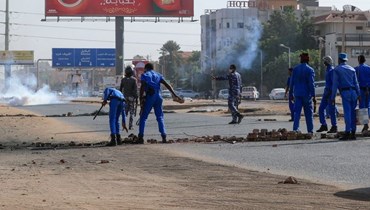 عناصر من قوات الأمن السودانية يزيلون حواجز وضعها متظاهرون في الخرطوم (أ ف ب).