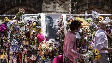 امرأة تحمل باقة أمام صورة لتوتو خارج كاتدرائية سانت جورج في كيب تاون (31 ك1 2021، أ ف ب). 