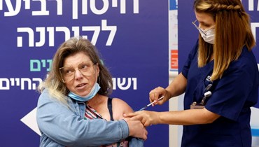 امرأة تتلقى جرعة رابعة من لقاح فايزر في مركز شيبا الطبي في رمات غان بالقرب من تل أبيب في اسرائيل (31 ك1 2021، ا ف ب). 
