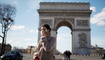 سيدة ترتدي كمامة واقية قرب قوس النصر بالعاصمة الفرنسية باريس (أ ف ب).