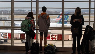 مسافرون ينتظرون في مطار رونالد ريغان الدولي في واشنطن (27 ك1 2021، أ ف ب). 