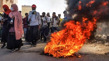 متظاهرون سودانيون يمرون قرب إطارات مشتعلة في الخرطوم (6 ك2 2022، أ ف ب). 