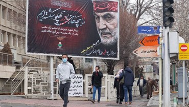 أشخاص يعبرون تحت صورة كبيرة لسليماني في طهران (2 ك2 2022، أ ف ب). 