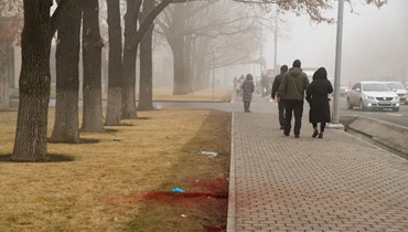 أشخاص يمرون قرب بقعة دماء على جانب الطريق في وسط ألماتي (6 ك2 2022، أ ف ب).  