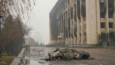 سيارة مدمرة أمام مبنى إداري محترق في وسط ألماتي (7 ك2 2022، أ ف ب). 