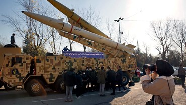 امرأة إيرانية تلتقط صورة لصاروخي "ذو الفقار بصير" و"دزفول" خلال عرضهما في طهران (7 ك2 2022، أ ف ب). 