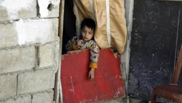 طفل لبنانيّ عند باب منزله في حيّ فقير من طرابلس (تعبيرية- أ ف ب).