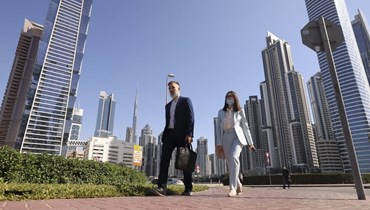 عاملان في دبي يوم الجمعة الأول من الدوام الرسمي (أ ف ب).