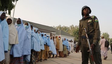 جندي يقف بجانب مجموعة من الفتيات اللواتي تم اختطافهن من مدرستهن الداخلية في شمال نيجيريا في 2 آذار 2021 (أ ف ب). 