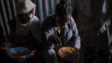 نازحتان جلستا في كوخ في مركز استقبال للنازحين في ميكيلي بمنطقة تيغراي بشمال إثيوبيا، لتناول طعام تبرع به سكان محليون (9 ايار 2021، ا ب). 